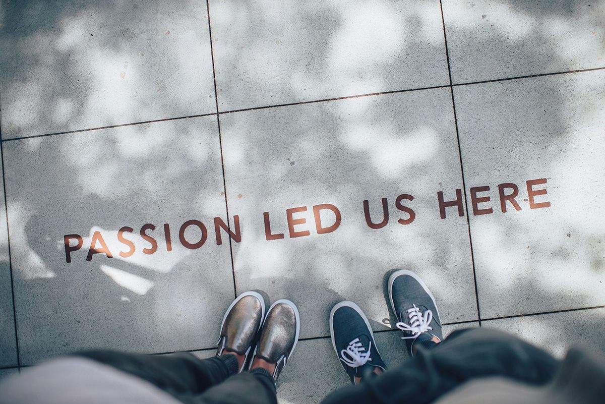 Cotora — deux personnes devant une enseigne au sol « Passion led us here »